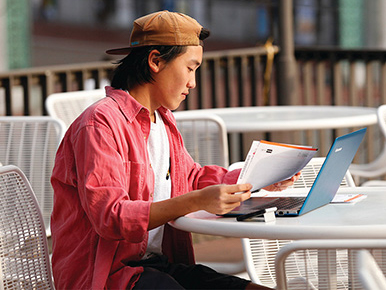 asian male student studying outside golden bear cafe patio